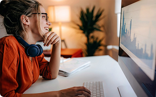 Junge Frau arbeitet am PC und lächelt.